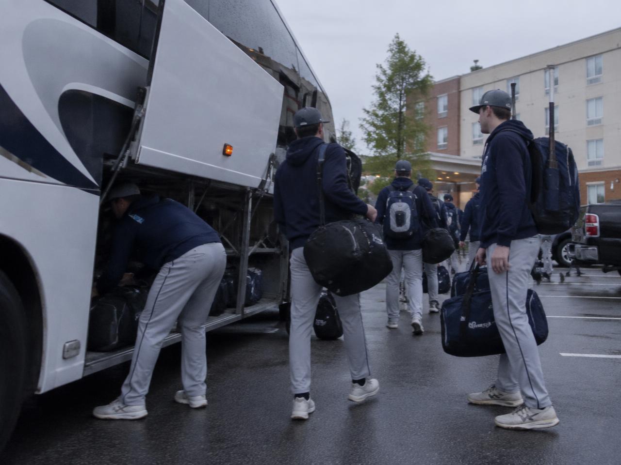 Team loading a bus outside a hotel